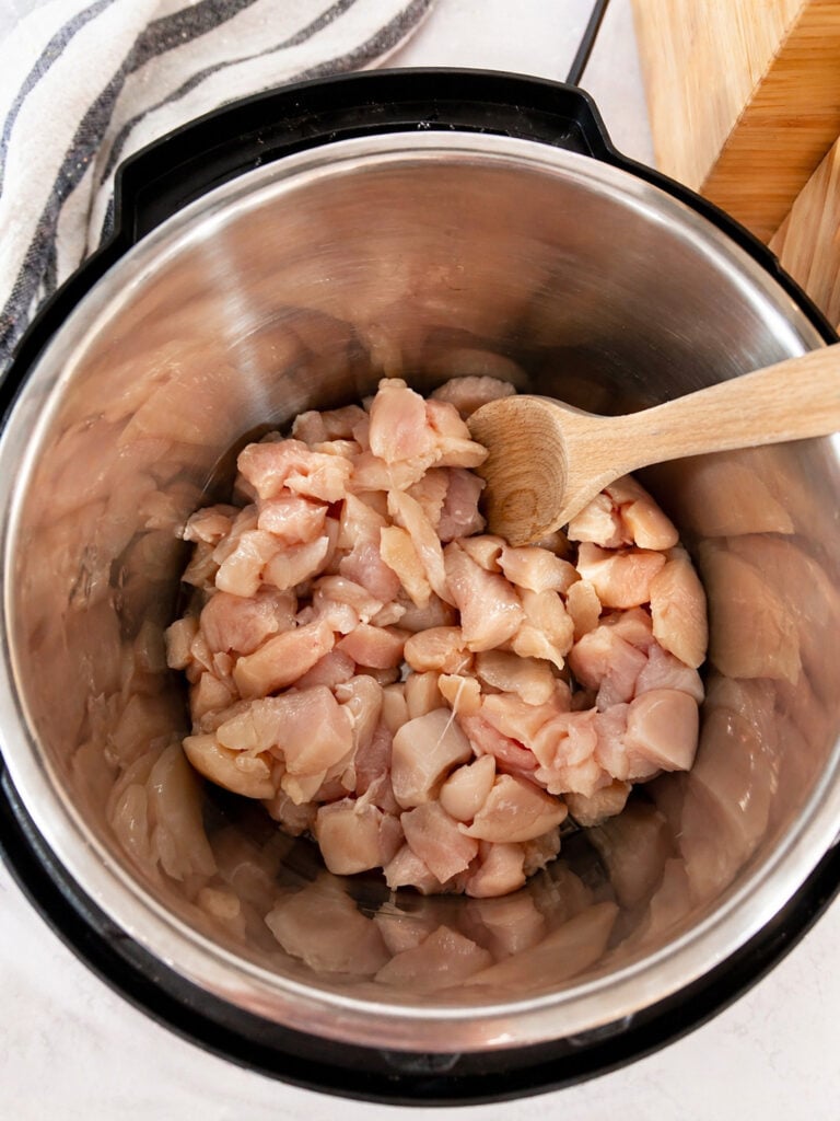 Raw diced chicken in Instant Pot before cooking chicken broccoli pasta