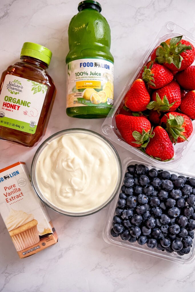Ingredients for the recipe. Honey, yogurt, vanilla, blueberries, strawberries, lemon juice. 
