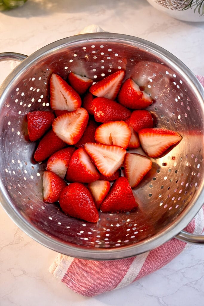 Freshly washed and sliced strawberries in a colander.