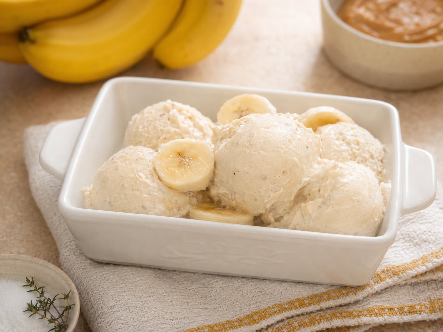 Homemade 3 ingredient banana ice cream scooped into a white serving dish and topped with fresh banana slices. This easy no-churn banana ice cream recipe is made with ripe bananas, heavy cream, and brown sugar for a creamy frozen dessert.