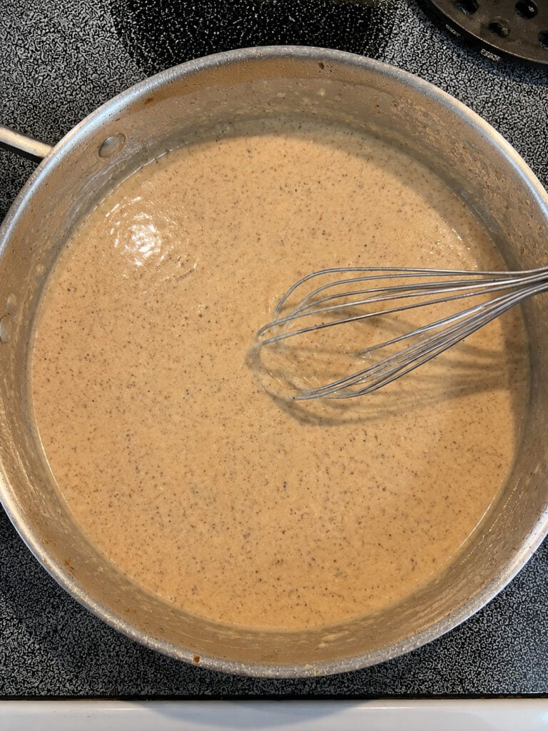 Homemade parmesan cream sauce whisked until smooth for steak topped with shrimp.