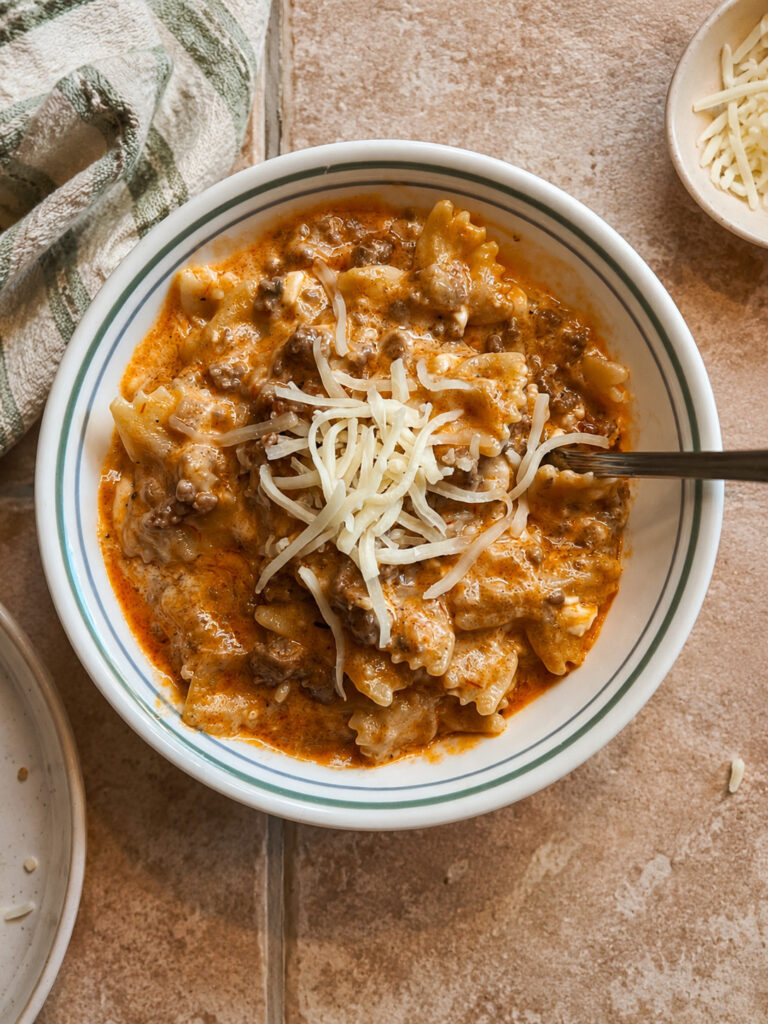 Bowl of cheesy instant pot lasagna casserole topped with shredded mozzarella cheese and ground beef in a white bowl