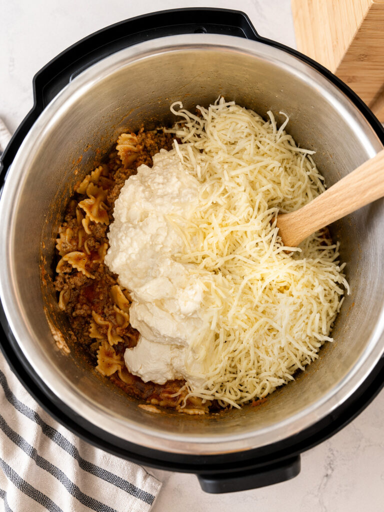 Ricotta cheese and shredded mozzarella added to cooked pasta and meat in the Instant Pot