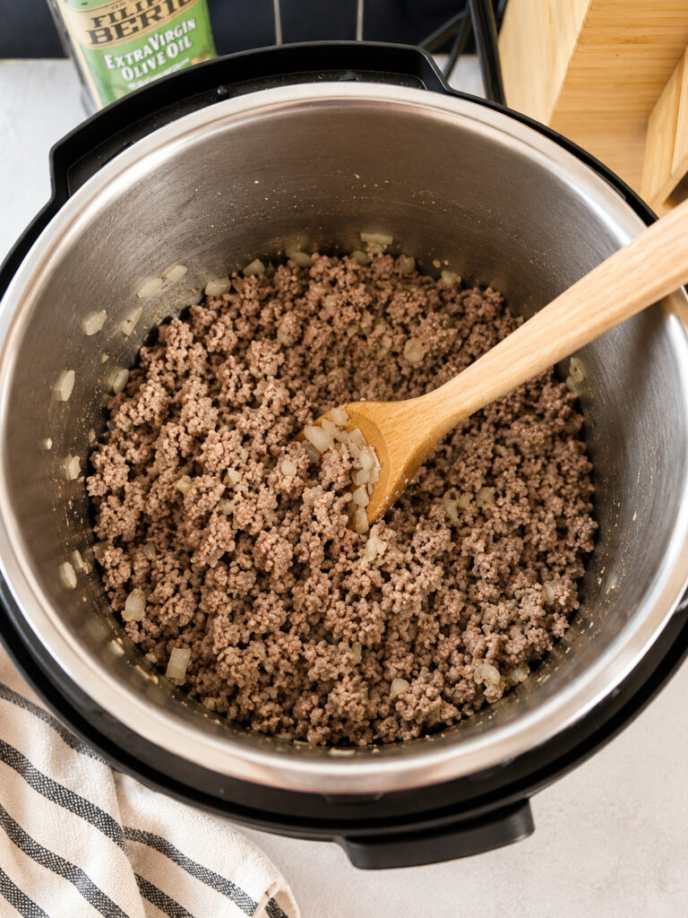 Cooked ground beef and onions browned inside an Instant Pot for pasta casserole