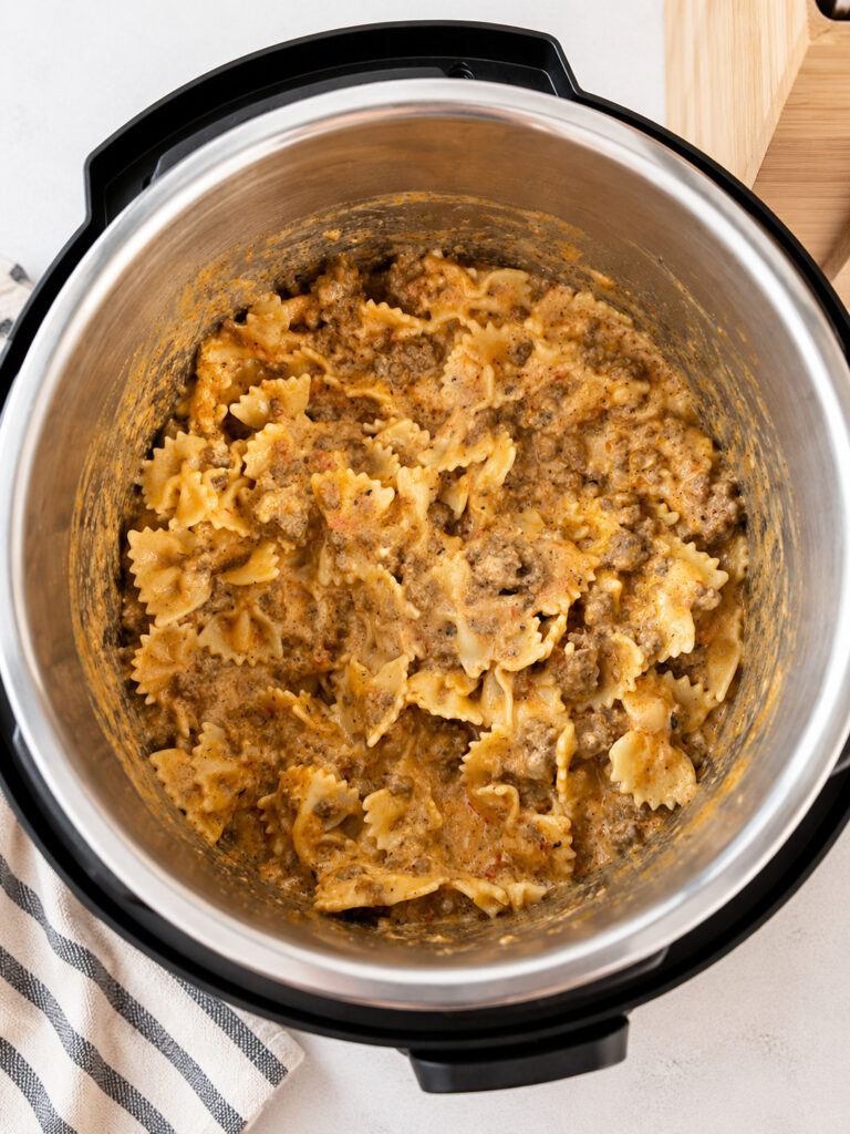 Creamy instant pot lasagna casserole with bow tie pasta and seasoned meat sauce in the pressure cooker