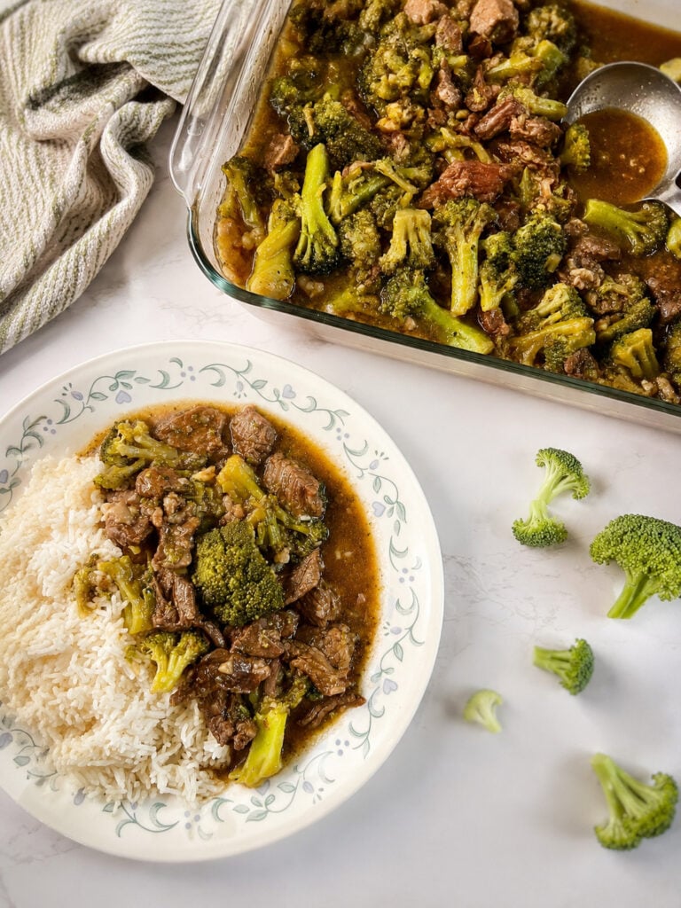 Homemade Instant Pot beef and broccoli served over white rice with extra broccoli and savory sauce in a glass baking dish.