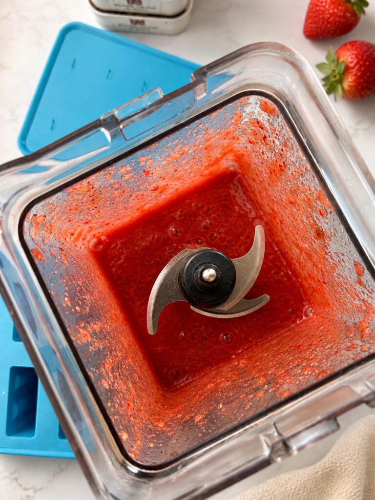 Blended strawberry puree in blender for making strawberry kiwi popsicles from scratch