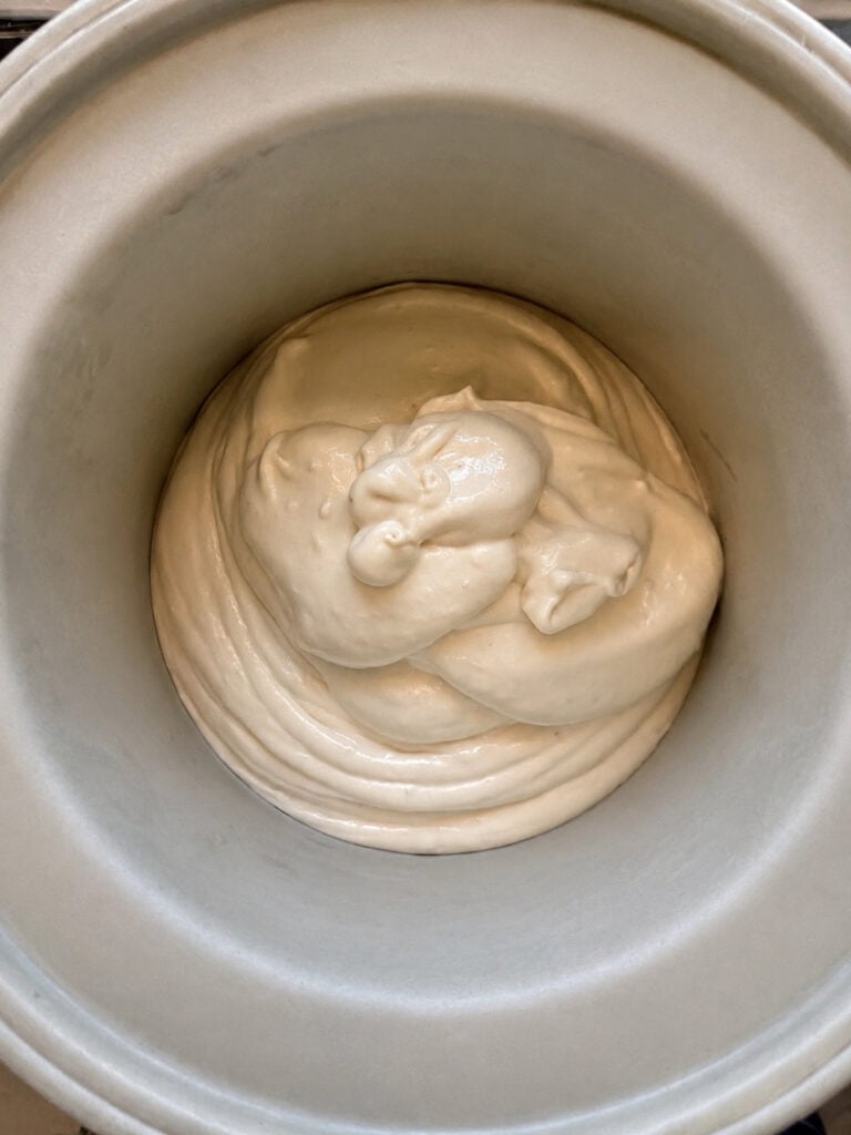 Creamy banana ice cream mixture poured into an ice cream maker before churning. Homemade banana ice cream base made with just three simple ingredients.