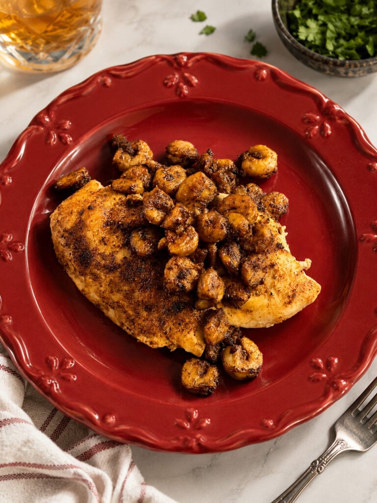 Copycat Bourbon Street chicken and shrimp featuring juicy seasoned chicken breast topped with garlic butter shrimp on a red plate.