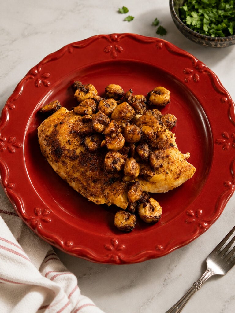 Bourbon Street chicken and shrimp served on a red dinner plate with a seasoned chicken breast topped with garlic butter shrimp.