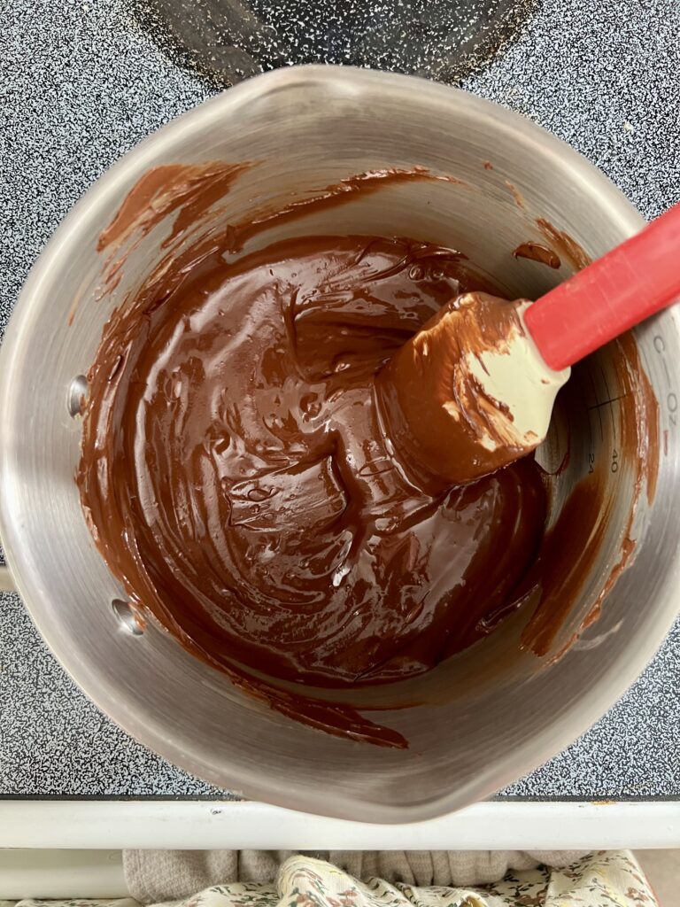 Smooth melted chocolate and peanut butter mixture stirred in a saucepan for no-bake chocolate Rice Krispie bars.