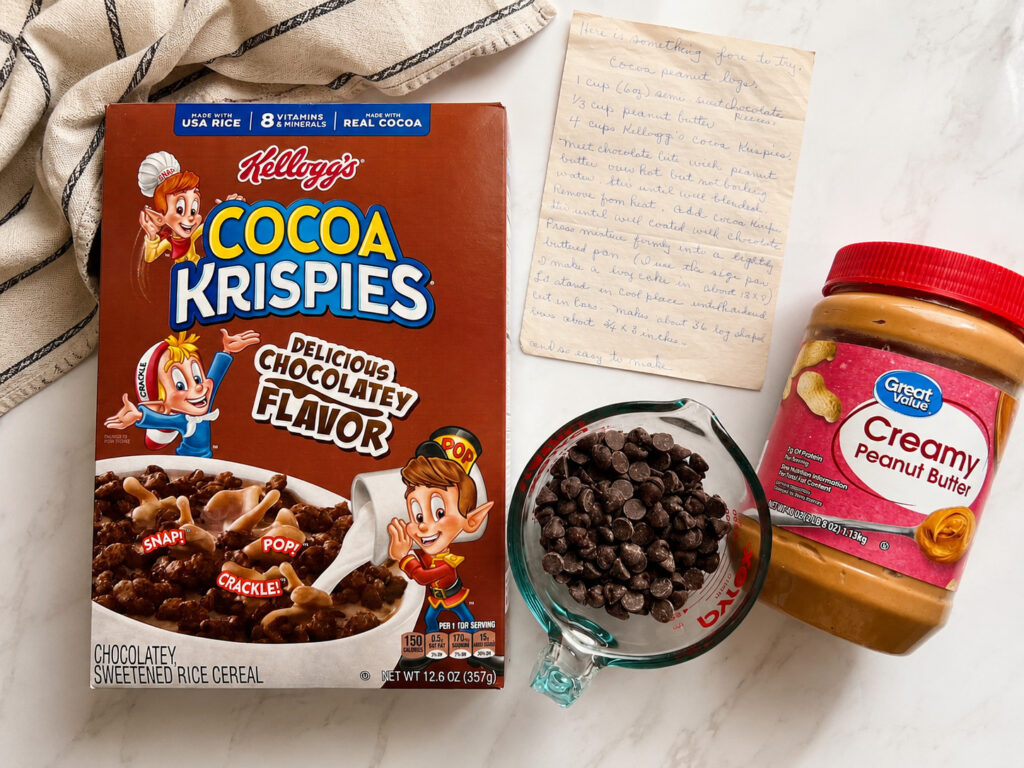 Ingredients for old-fashioned chocolate Rice Krispie bars including Cocoa Krispies cereal, peanut butter, chocolate chips, and a handwritten family recipe card.