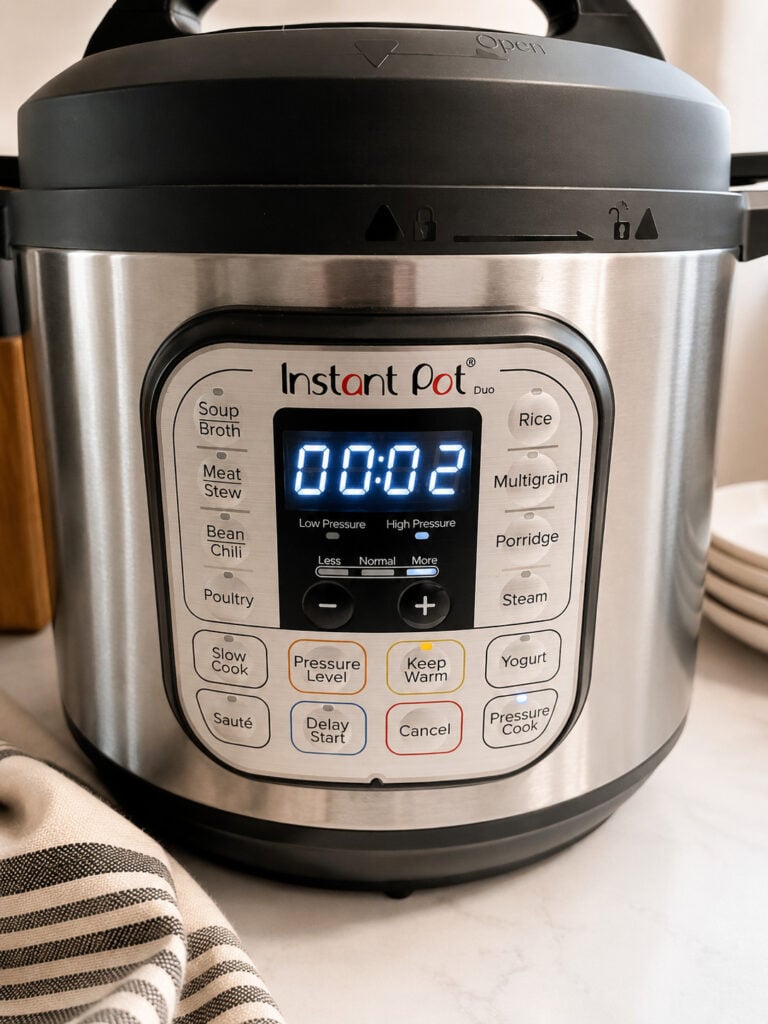 Close-up of a 6-quart Instant Pot Duo pressure cooker set to cook for 2 minutes, displayed on a kitchen countertop with a striped kitchen towel nearby.
