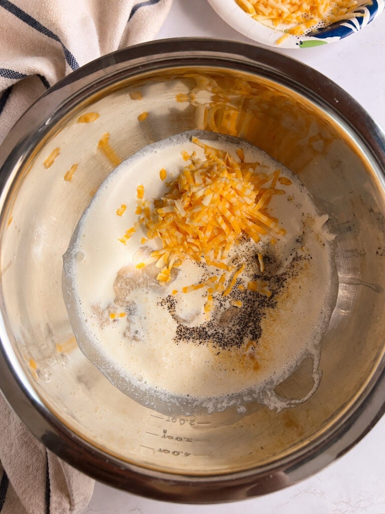Cheese, cream, sour cream, seasonings, and cream of mushroom soup combined in an Instant Pot insert to make the creamy sauce for scalloped potatoes.