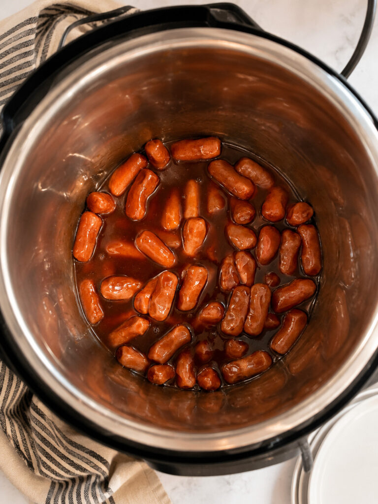 Little Smokies cocktail sausages coated in barbecue sauce inside an Instant Pot, ready to be pressure cooked.