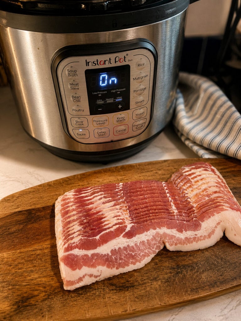 Package of sliced bacon on a wooden cutting board in front of an Instant Pot, ready for cooking.