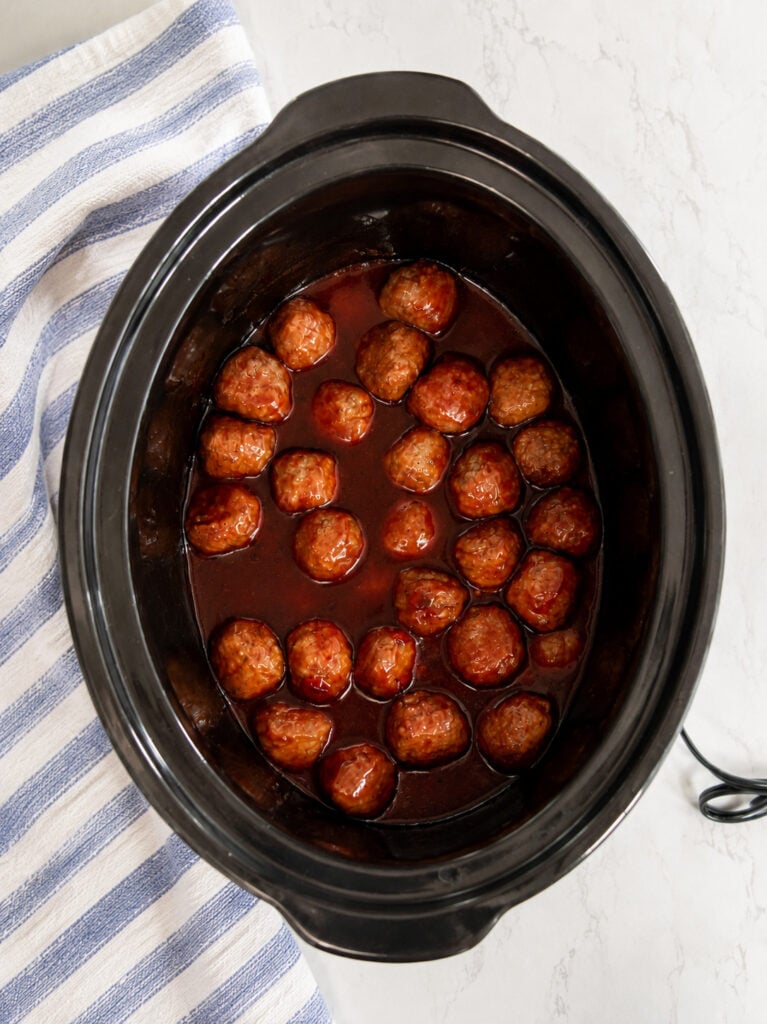 Tender meatballs coated in a rich sweet and smoky barbecue sauce after cooking in the slow cooker.