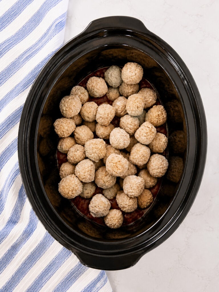 Frozen meatballs layered over barbecue sauce and grape jelly before slow cooking in a crockpot.