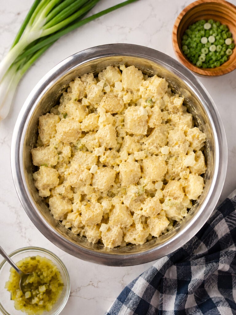 Freshly mixed creamy potato salad with tender potatoes, chopped eggs, and pickles ready to chill before serving at a barbecue or picnic.