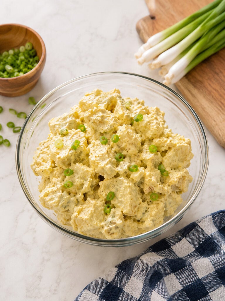Old-fashioned creamy potato salad garnished with sliced green onions in a glass serving bowl, perfect for cookouts, potlucks, and family dinners.