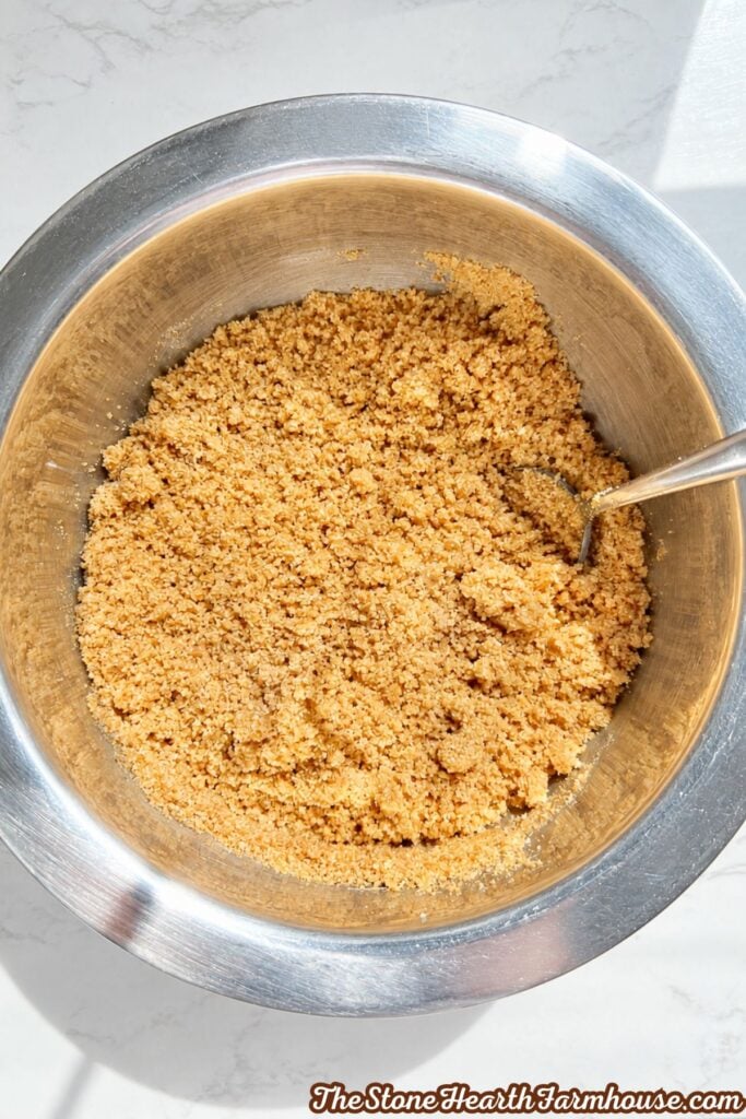 Prepared graham cracker crumb mixture ready to be pressed into a springform pan