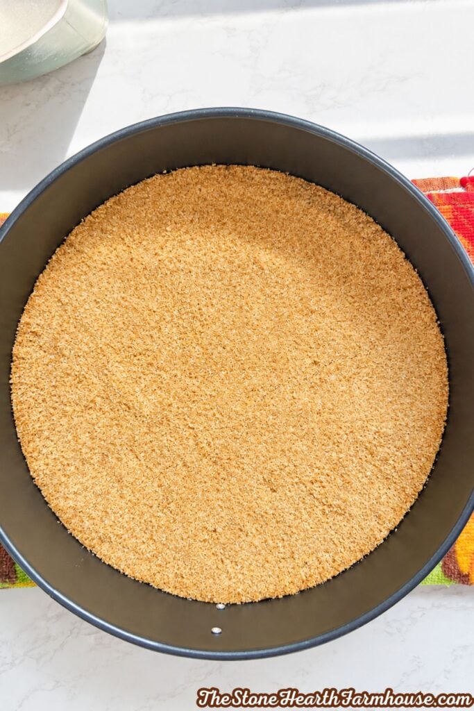 Baked graham cracker crust pressed evenly into a springform pan.