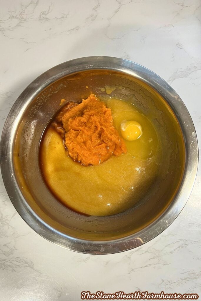 adding egg and pumpkin puree to the bowl. 