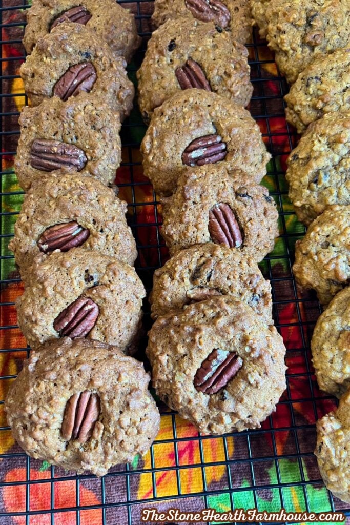 pumpkin cookies with half pecan on top, cooling on a cookie rack. 