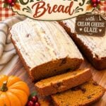 Pumpkin cranberry bread with cream cheese glaze, sliced and served on a wooden board with pumpkins and cranberries