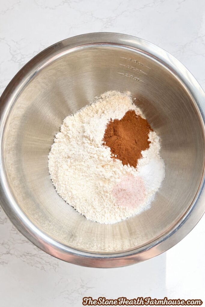 Flour, pumpkin pie spice, baking soda, and salt combined in a stainless steel mixing bowl