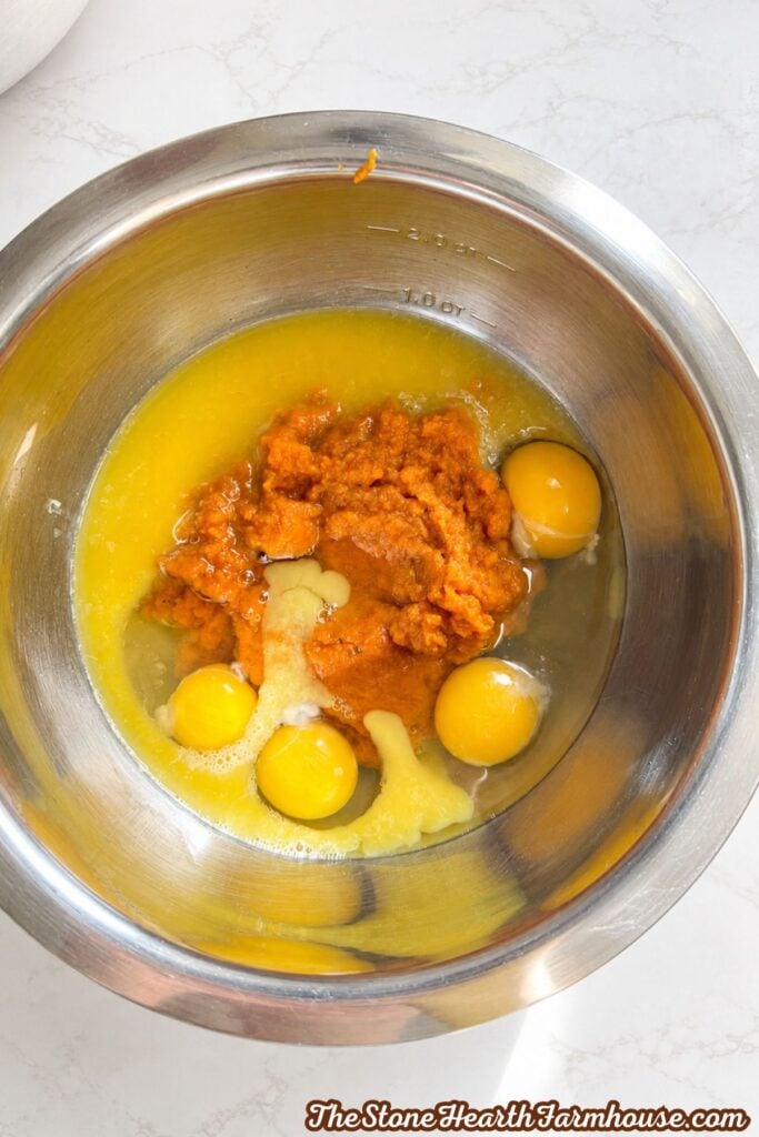Pumpkin purée, eggs, melted butter, and orange juice in a stainless steel mixing bowl