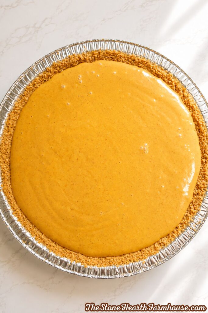 Pumpkin cheesecake filling spread evenly over a prepared graham cracker crust