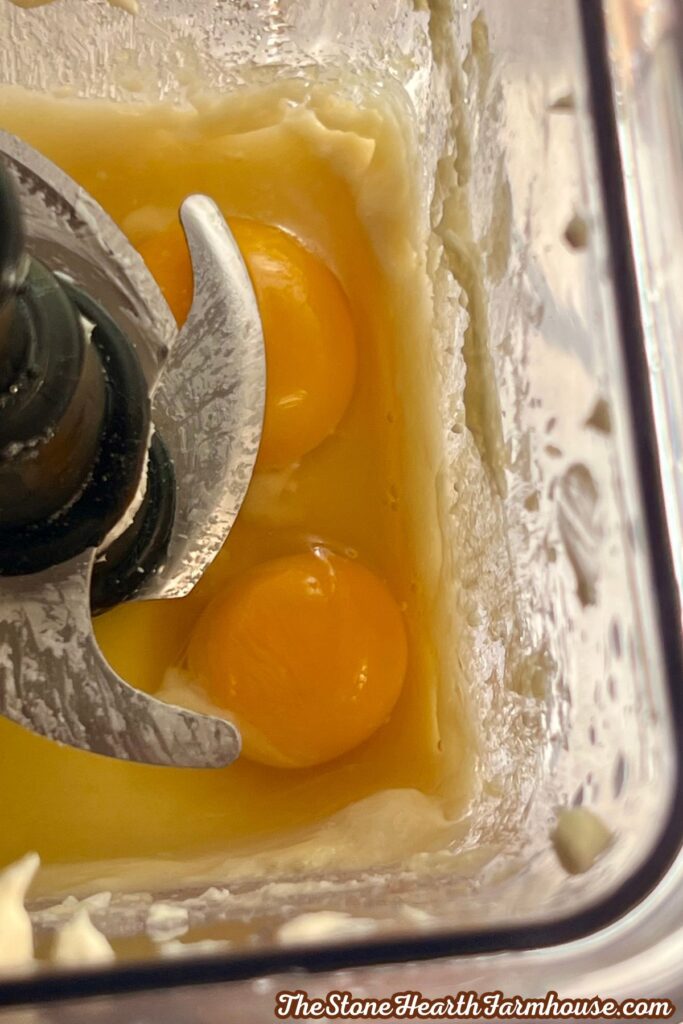 Eggs and creamy pumpkin cheesecake filling being blended in a food processor